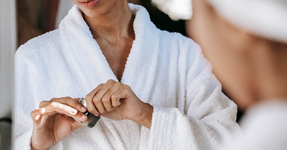 Young woman applying skincare cream in a bathrobe, reflecting self-care and wellness at home.