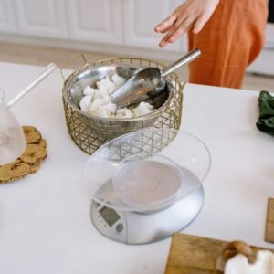 A person crafting handmade candles in a cozy kitchen with natural materials.